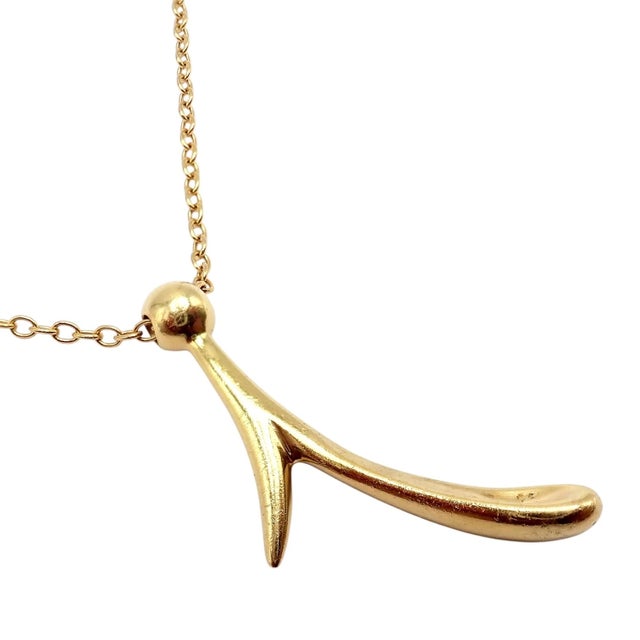 This vintage Tiffany & Co. Elsa Peretti necklace crafted in 18k gold, features a sculptural initial “I” pendant on a long...