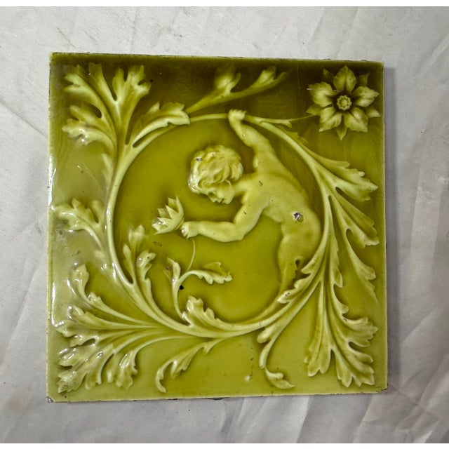 This antique 19th century Minton Hollins ceramic pottery tile features a green glaze with cherub design, making it a...