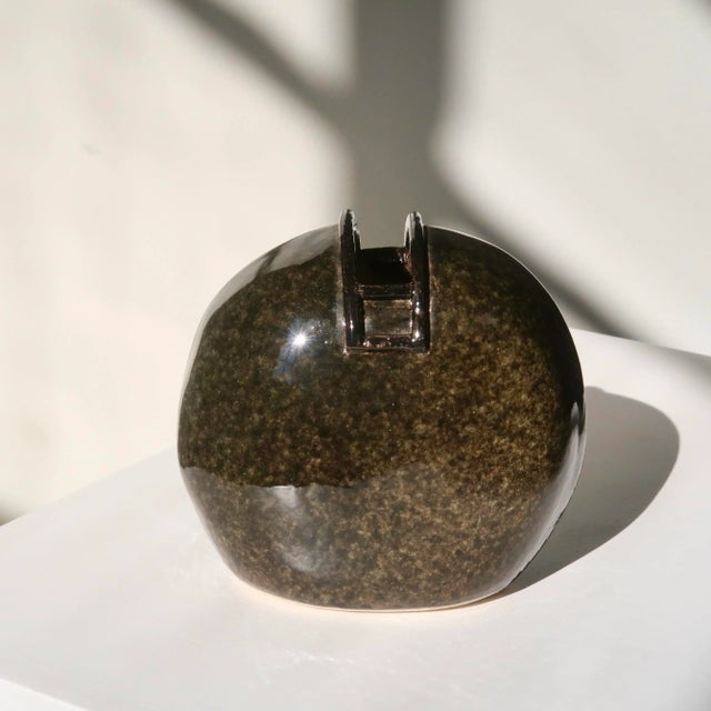 A beautifully crafted studio pottery bud vase featuring a deep earth tone glaze with subtle mottling, giving the piece an...