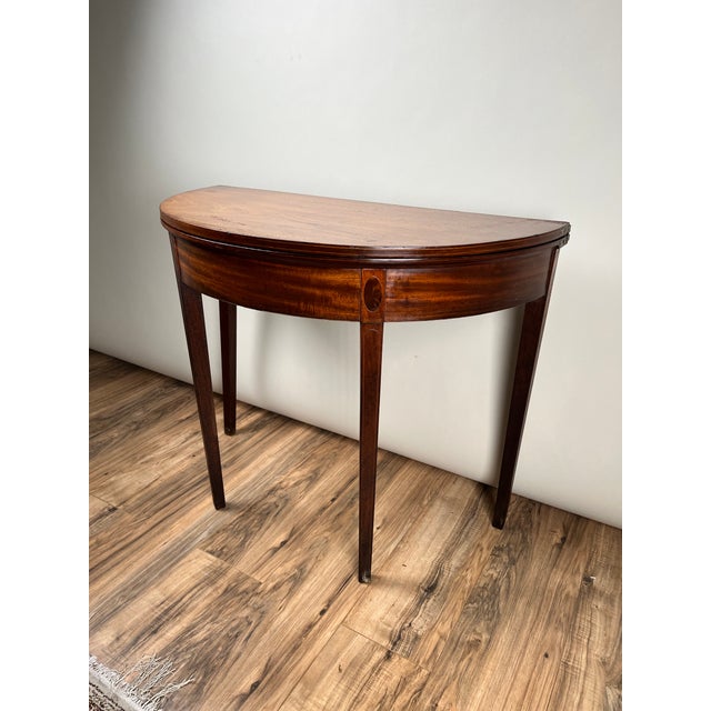 A handsome mid-19th century Hepplewhite demilune game table in mahogany, displaying the refined simplicity and elegant...