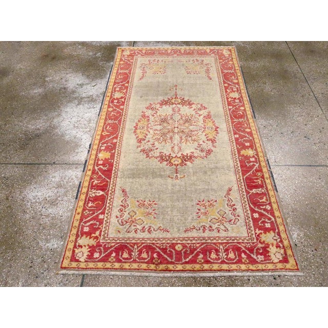 An antique Turkish Oushak accent rug. A bilaterally symmetric oval bouquet medallion with floral garland corners is set on...