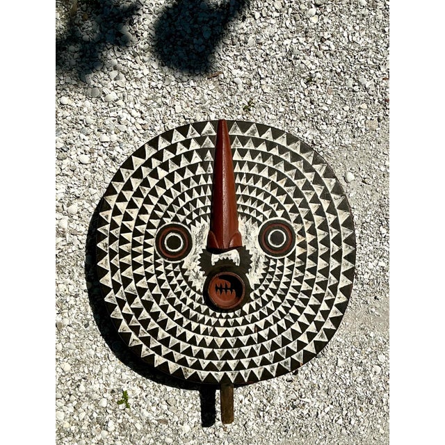 This vintage tribal geometric painted wood shield is a visually arresting example of traditional craftsmanship and...