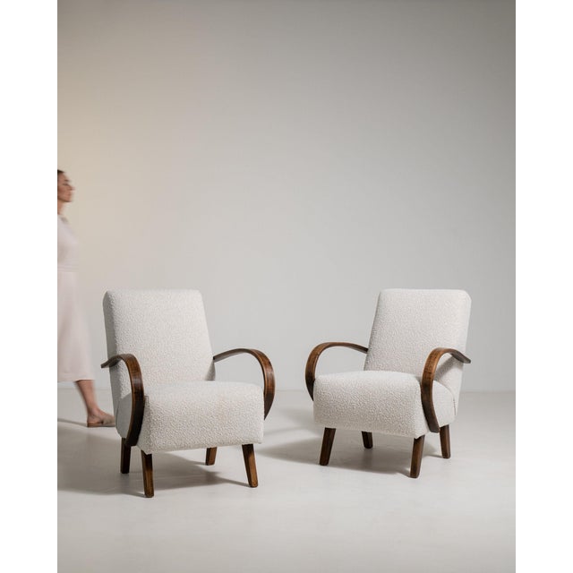 Pair of bentwood-arm lounge chairs in Warm Ivory Boucle. The warm ivory boucle surface highlights curved wood open arms,...