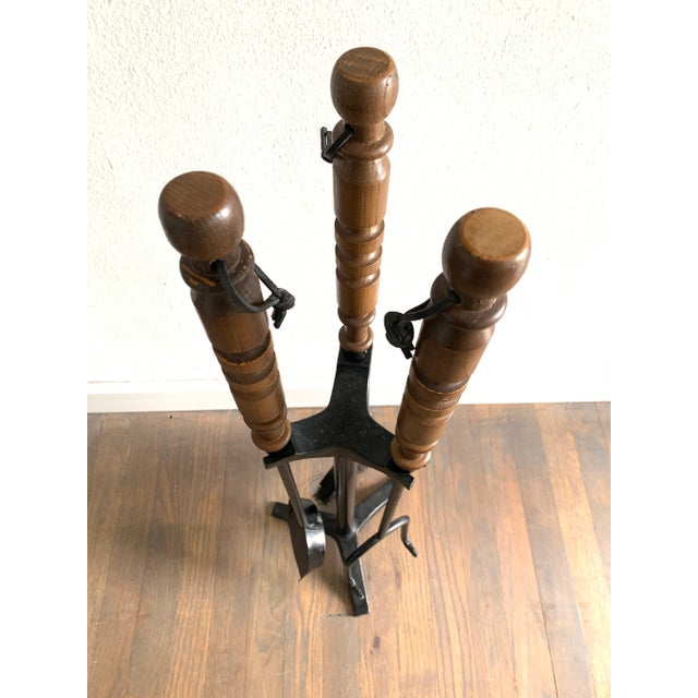 A handsome set of mid-century modern fireplace tools featuring turned wood handles and heavy metal construction.