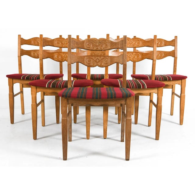 Set of six oak dining chairs designed by Henning Kjærnulf and produced by EG Møbler. The chairs feature carved decorative...