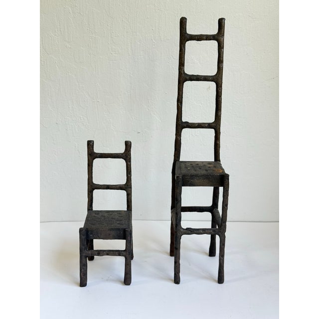 Set of two graduated cast iron ladderback style chair sculptures. Giacometti style with their elongated presence. Larger...