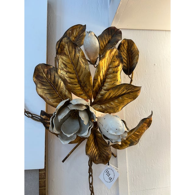 Pair of 1950s Italian wall sconces featuring gilt metal leaves with enamel floral details and original chain accents....