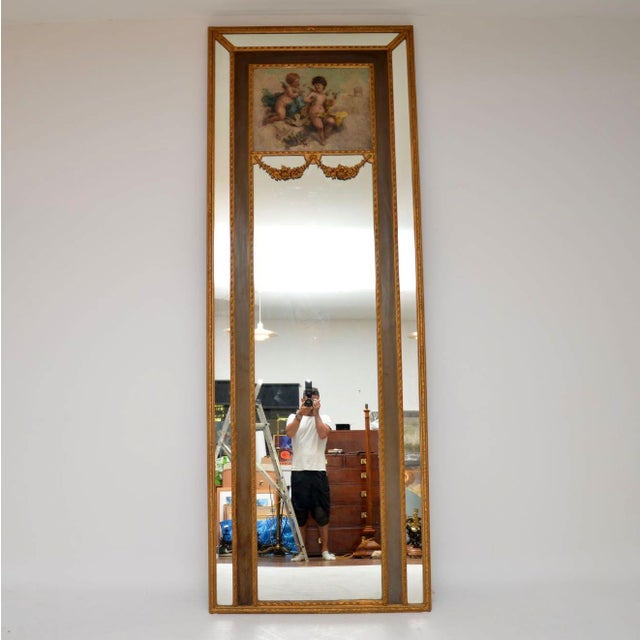 Tall antique decorative gilt wood mirror with a signed oil painting on the top section some other wonderful features. It’s...