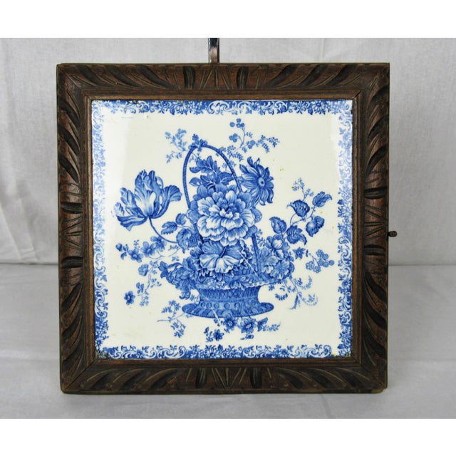 An antique circa 1880’s French tile music box trivet. White tile with a blue floral basket design. Hardwood frame...