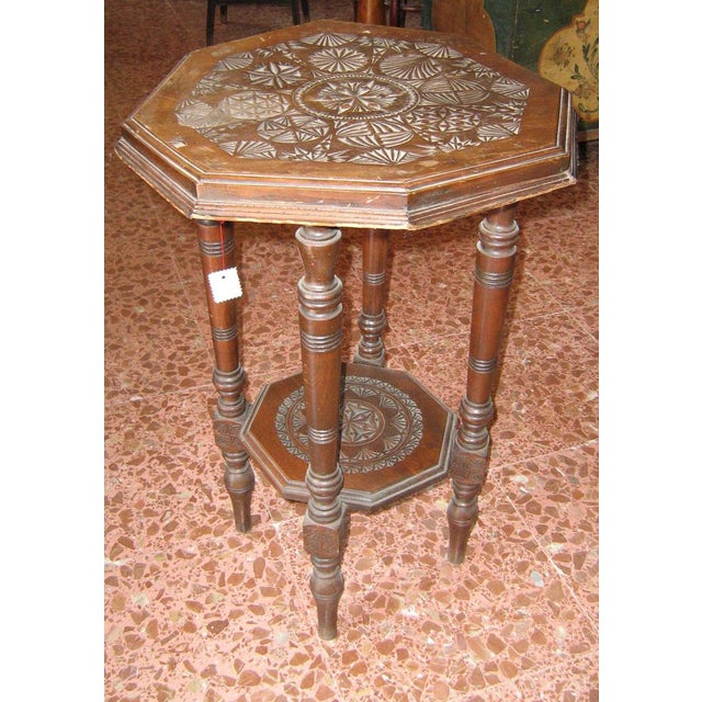 Liberty octagonal coffee table in walnut-stained wood, with a carved top that has become "spoiled" over time....