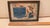 Framed color print of small black boy and his dog admiring a cake and pie with motto: "Through fear of taking risks in...