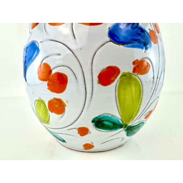 This vintage Italian ceramic vase is a vibrant display of hand-painted craftsmanship. Adorned with colorful floral and...