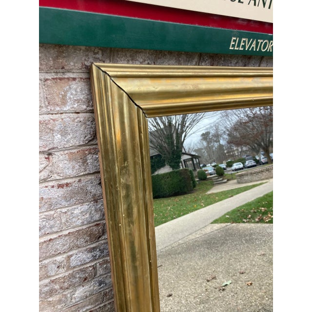 Large over mantel mirror with an unlacquered brass frame.