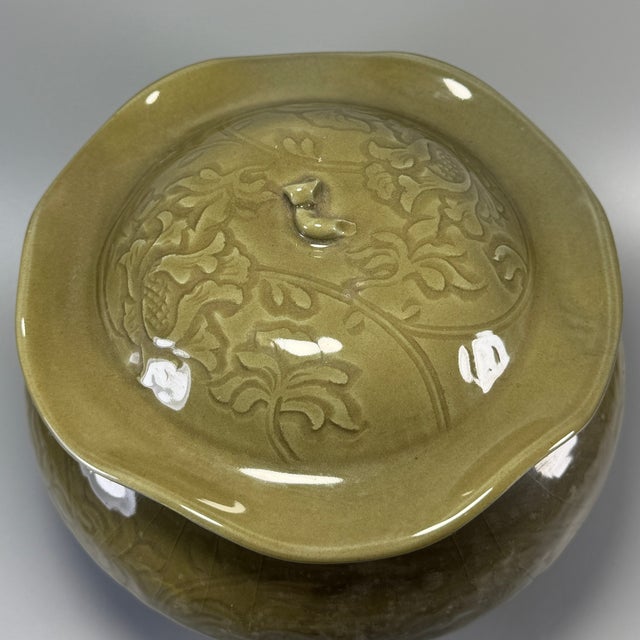 Graceful Chinese celadon lidded jar with elegant lotus‑leaf form cover. The exterior is decorated with fine carved floral...