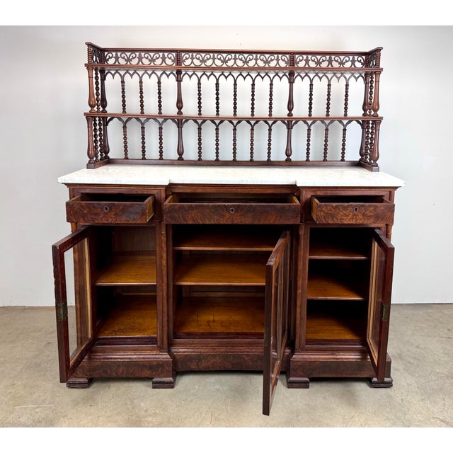A magnificent, large Victorian-style mahogany sideboard or buffet featuring a marble top, glass-front cabinet doors, and...