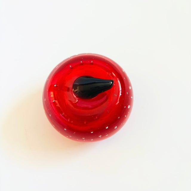 A vintage art glass apple paperweight. Vibrant red color to the glass with a green stem. Beautiful controlled bubbles to...