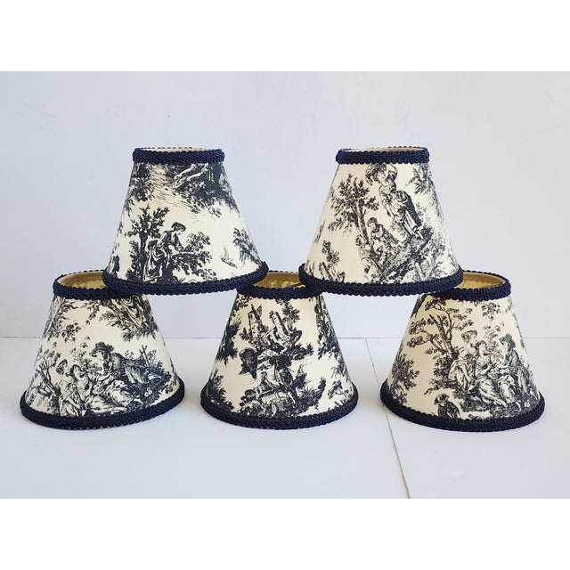 Set of 5 French Toile 18th century motifs and sceneries chandelier shades with dark blue gimp trim piping. The shades have...