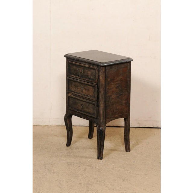 A French painted wood side chest with marble top from the 19th century. This smaller-sized commode from France has a black...