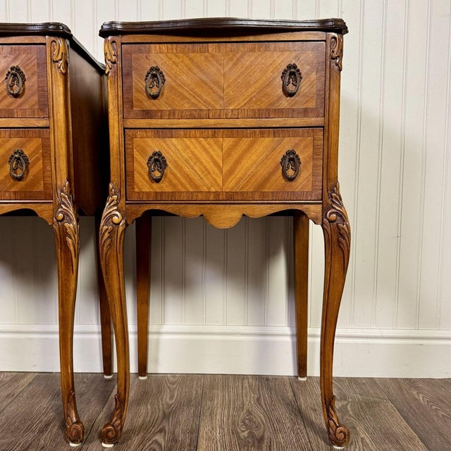 Vintage French Provincial nightstand pair with diamond-matched veneer and Louis XV-style carving. Each nightstand features...