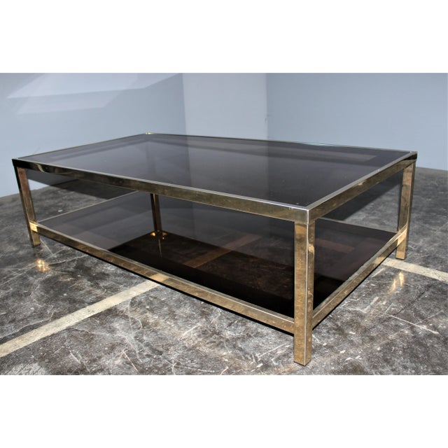 Golden metal with 23 carat fine gold. The glass shelves edged with bronze mirrors strip 7 cm are original. This piece is...