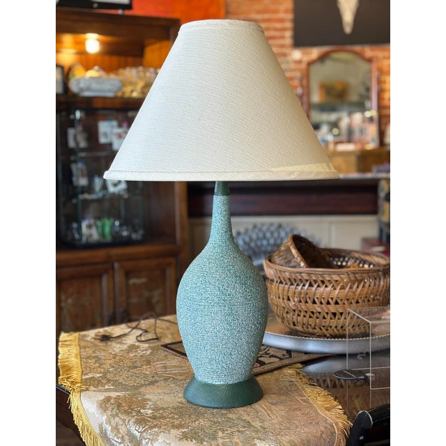 Classic, vintage MCM table lamp in soft green, pebbled texture. There is a band of darker green at the bottom and top of...