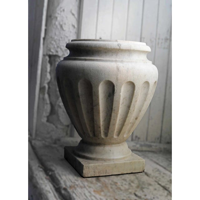 Pair of vintage, Neoclassical style white Carrara marble fluted jardinière planters. Originating from Italy in the...