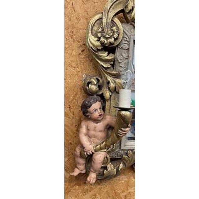 Ornate giltwood framed vanity mirror with three cherubs, two cherubs making the mirror a functioning light fixture....