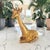 Large gilt chalkware giraffe sculpture produced in the United States during the 1970s. Executed in a reclining pose with...