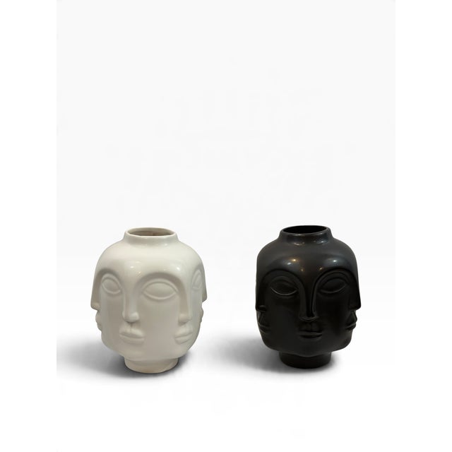 A striking pair of sculptural ceramic vases, each molded with overlapping serene faces that shift as you move around the...