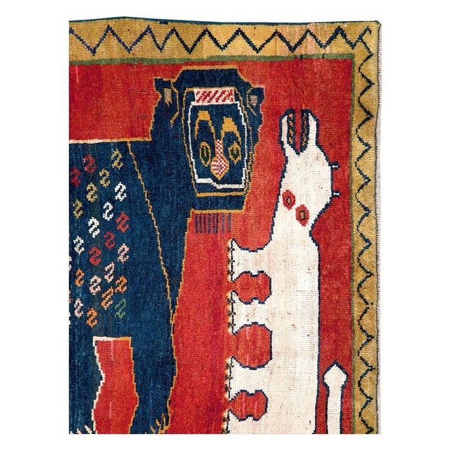 This mid-20th-century Persian Pictorial Shiraz rug presents a bold figurative composition centered on a large dark blue...