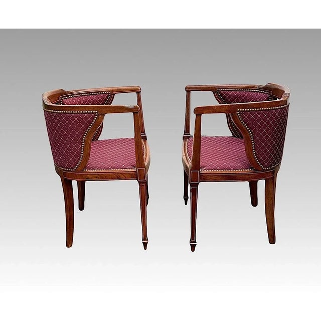 A very fine pair of antique Edwardian club chairs made of solid figured mahogany in classic form with contrasting string...