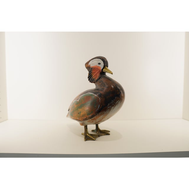 A charming hand-painted wooden bird sculpture featuring layered color and expressive detailing. This freestanding...
