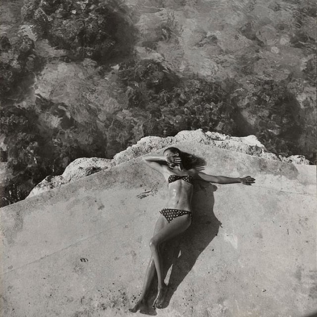 The Bikini by Toni Frissell Fashion model Natahli (Natalie) Nickerson Paine wearing a bikini, lying on a platform near...