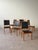 Set of six vintage Danish dining chairs featuring teak frames with tall upholstered backs and padded seats in black vinyl...
