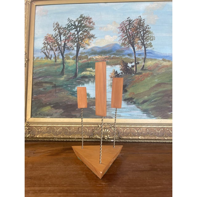 Mid-century modern three-arm candle holder featuring a minimalist geometric design. The triangular possibly teak wood base...