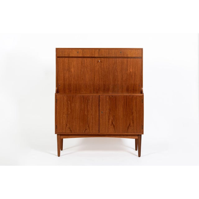 This vintage mid-century Danish modern teak secretary cabinet was made in Denmark in the 1960s. It exemplifies classic...