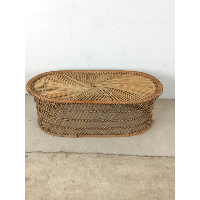 This vintage boho chic coffee table features rattan construction, original finish, and oval shaped design.