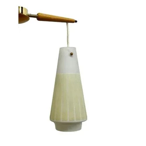 A mid 20th Century beech color wooden triangle base lamp with three frosted glass shades with vertical light yellow...