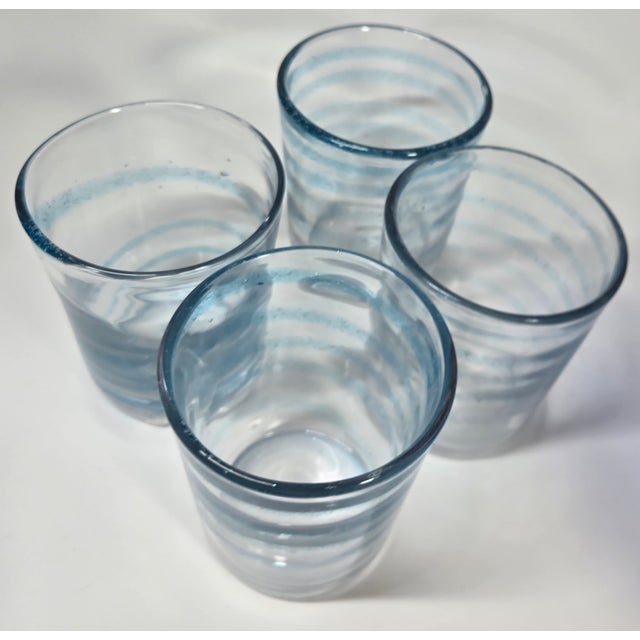 Transparent blue swirls through this lightly bubbled handblown double old fashioned glasses.