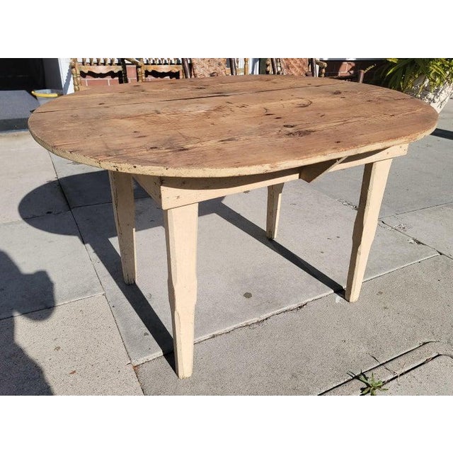 This fine hand made oval farm table is in original cream painted surface and square nail construction.The scrub or...