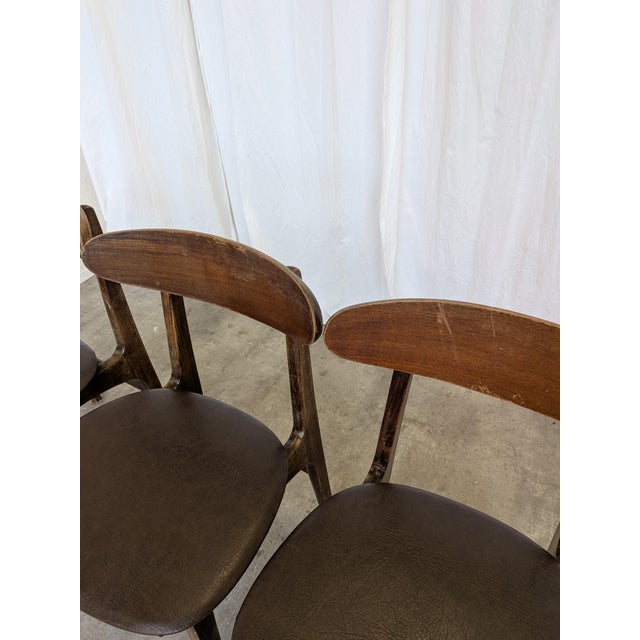 Vintage wooden dining chairs dating to the 1960s–1970s. The chairs have a simple mid-century modern design with solid wood...