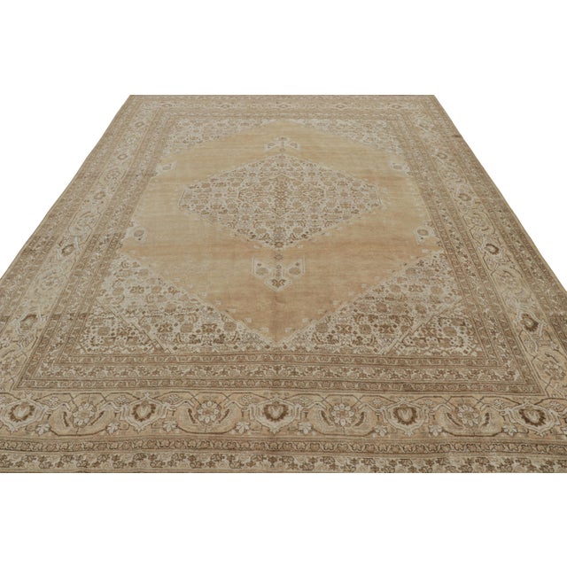Hand-knotted in luxurious wool, this 9x12 antique Persian Tabriz rug features a rich design combination of floral...