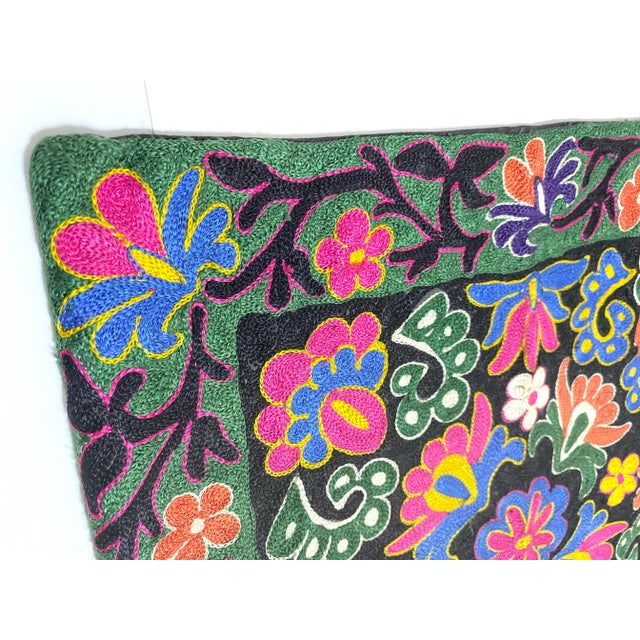 A stunning vintage Suzani embroidered pillow cover featuring vibrant floral motifs hand-stitched in traditional Uzbek...