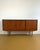 A 1960s danish teak sideboard with three sliding doors and handles carved into the front. The profile is simple and...