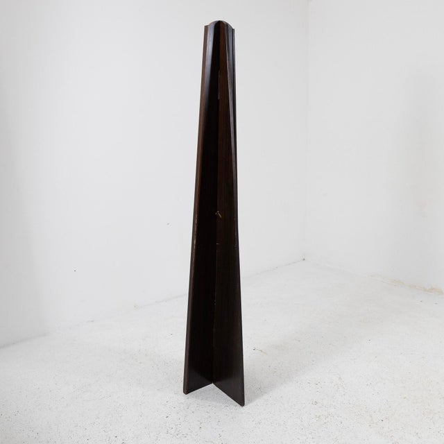 A floor-standing mirror with clean, slender lines, featuring a wooden frame that tapers toward the top. The sloping sides...