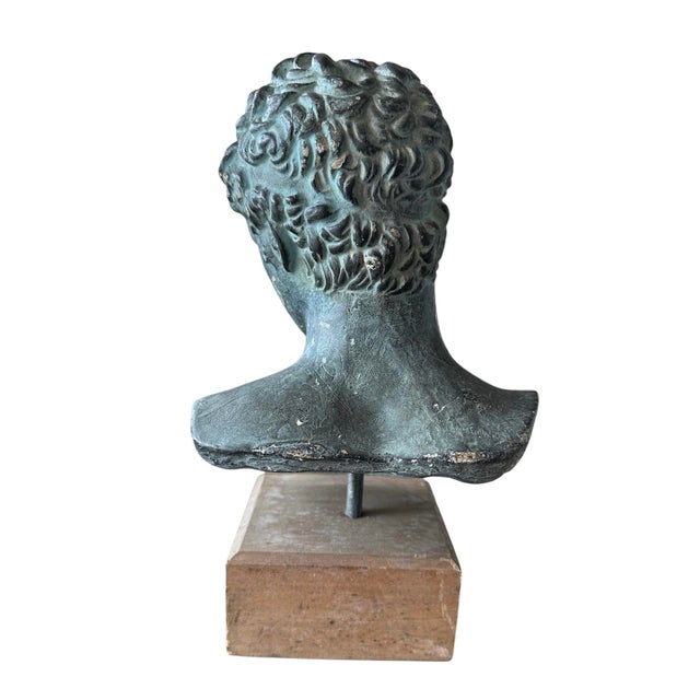 Vintage Head Bust crafted in plaster in a verdigris finish, elegantly showcased on a distressed wooden stand. This...
