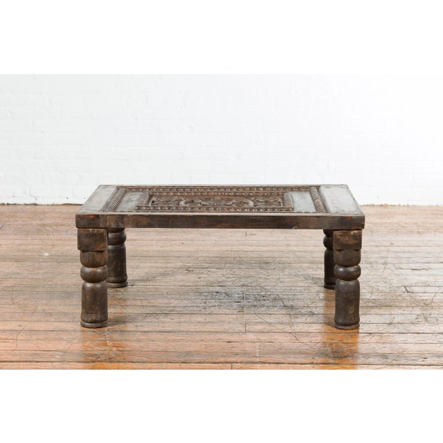 An Indian antique small coffee table from the 19th century, with carved wooden floral motifs and baluster legs. Created in...
