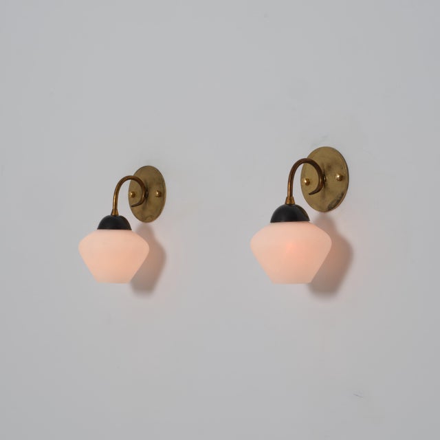 Pair of Italian wall sconces from the 1950s characterized by a compact and balanced mid-century design. Each fixture is...
