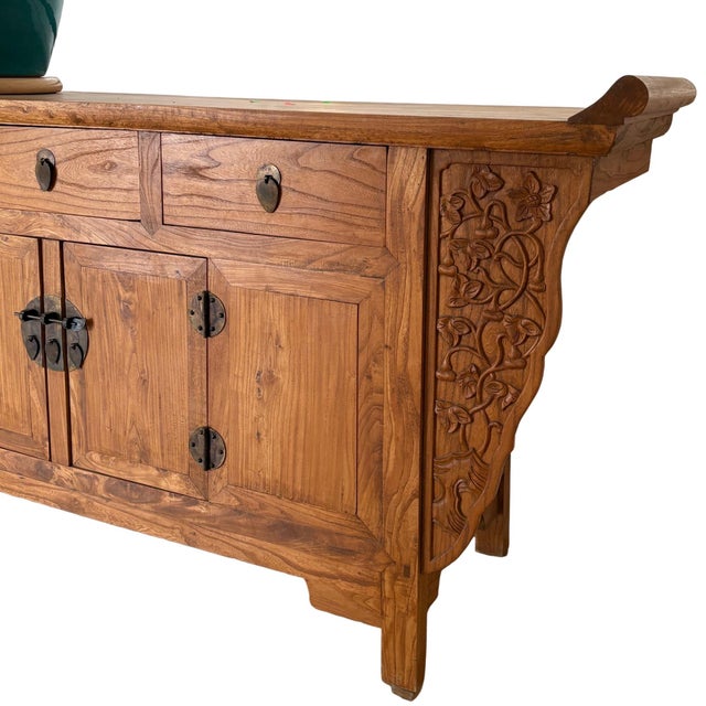 Beautiful antique Chinese elm sideboard featuring hand-carved side panels and traditional brass hardware. Solid wood with...