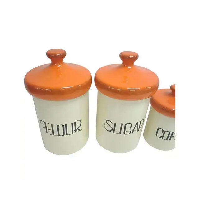 Mid-Century canister set of four in off white ceramic with bright 60's orange lids. Four canisters in all, all in good...